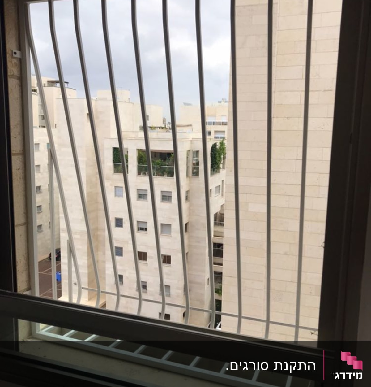 סורגי מתכת על חלון עם נוף לבניינים
